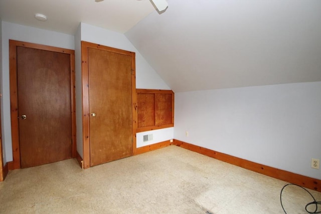 additional living space with baseboards, visible vents, and lofted ceiling