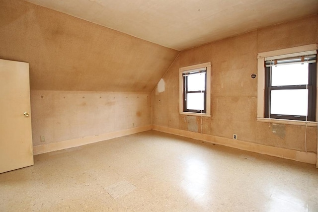 additional living space with baseboards and lofted ceiling