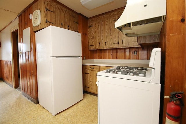 kitchen with white appliances, exhaust hood, brown cabinetry, and light floors