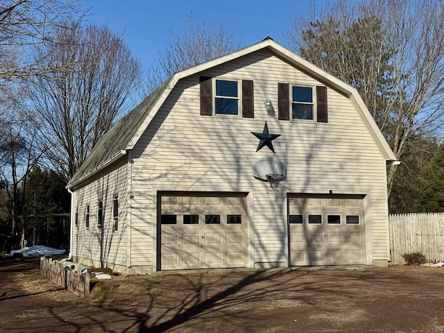 view of side of property featuring a garage, a gambrel roof, and fence