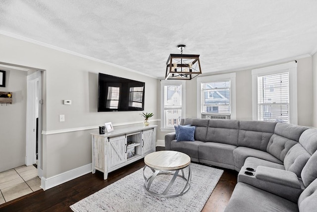 living room with a chandelier, a textured ceiling, dark wood-type flooring, baseboards, and ornamental molding