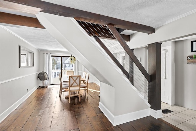 interior space with wood-type flooring, a textured ceiling, baseboards, and beam ceiling