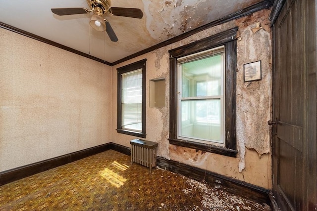 empty room with radiator heating unit, baseboards, crown molding, and a ceiling fan