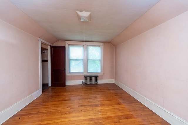 bonus room with radiator heating unit, vaulted ceiling, light wood finished floors, and baseboards