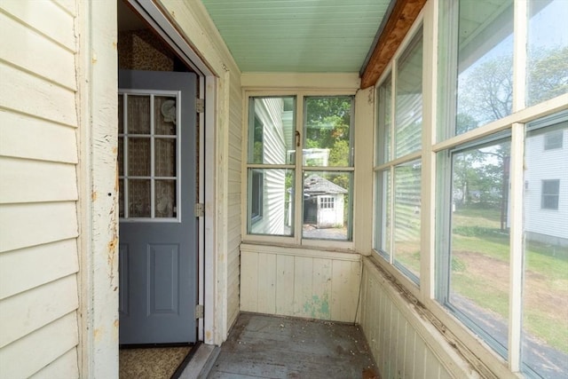 unfurnished sunroom with healthy amount of natural light and wood walls