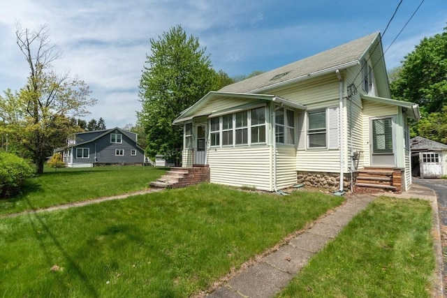 view of front of property with entry steps, a front yard, a sunroom, and a garage