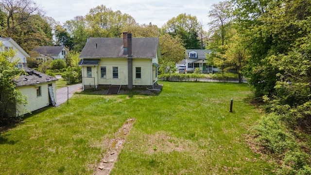 back of house with a chimney, a yard, and view of scattered trees