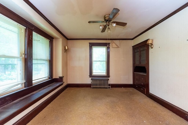 carpeted empty room with radiator heating unit, baseboards, a ceiling fan, and ornamental molding