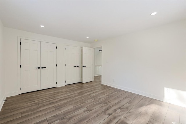 unfurnished bedroom with light hardwood / wood-style floors and multiple closets