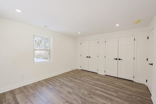 unfurnished bedroom featuring two closets and light hardwood / wood-style floors