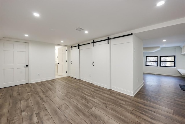 interior space with a barn door and wood-type flooring