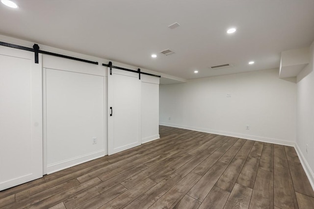 basement featuring a barn door and hardwood / wood-style flooring