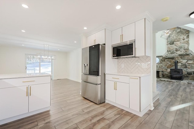 kitchen featuring white cabinets, stainless steel appliances, and a wood stove