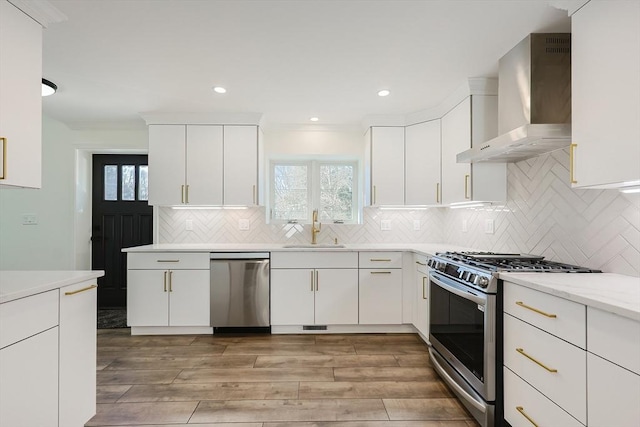 kitchen with white cabinets, appliances with stainless steel finishes, wall chimney exhaust hood, and sink