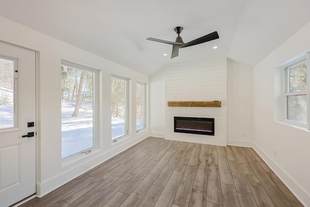 unfurnished living room featuring ceiling fan, light hardwood / wood-style flooring, a fireplace, and vaulted ceiling