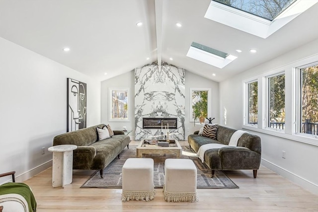 living room featuring vaulted ceiling with skylight and light hardwood / wood-style floors