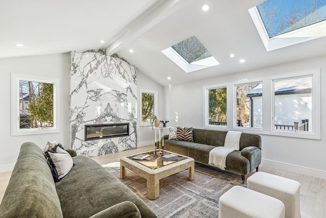 living room with hardwood / wood-style flooring, a fireplace, and lofted ceiling with skylight