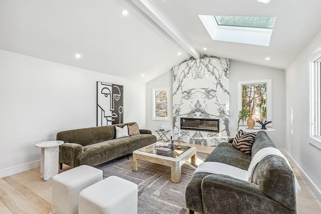 living room with a fireplace, a wealth of natural light, lofted ceiling with skylight, and light wood-type flooring