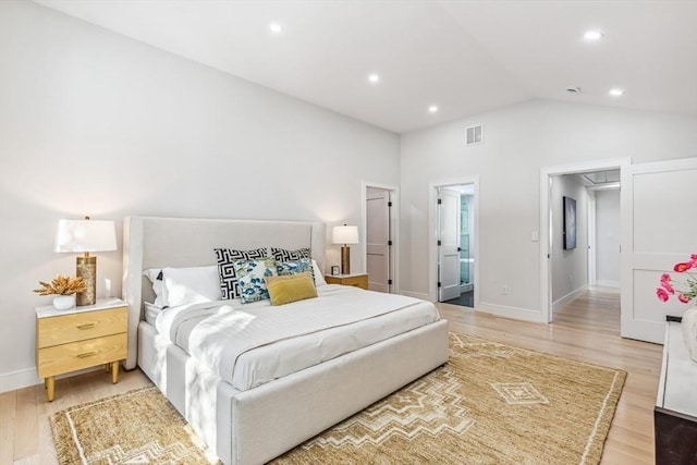 bedroom featuring vaulted ceiling, ensuite bath, and hardwood / wood-style floors