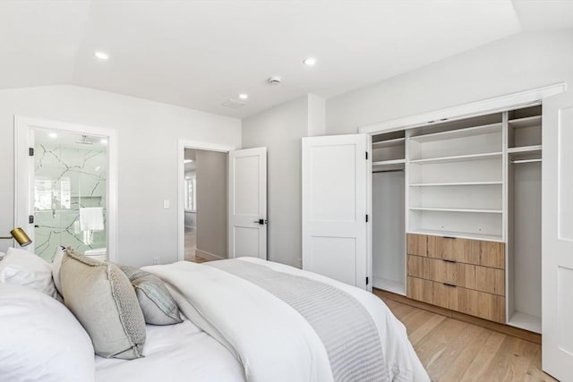 bedroom featuring light hardwood / wood-style floors, vaulted ceiling, and a closet