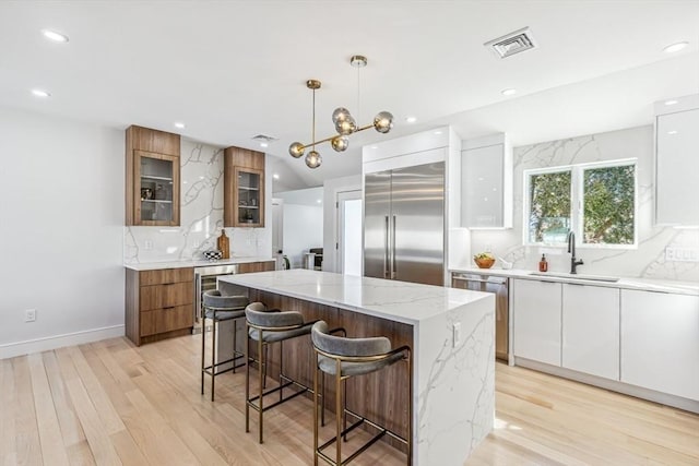 kitchen with pendant lighting, sink, stainless steel appliances, white cabinets, and a kitchen island