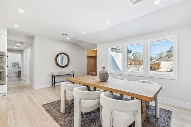 dining space featuring lofted ceiling and light hardwood / wood-style flooring