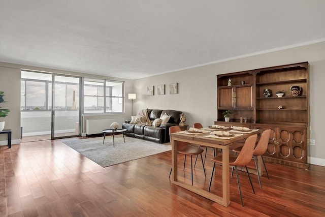 dining space featuring dark wood-type flooring, crown molding, and a water view