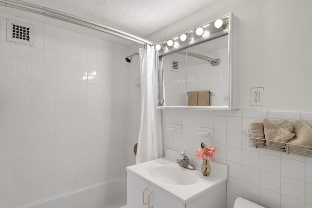 full bathroom with a textured ceiling, vanity, shower / tub combo, tasteful backsplash, and tile walls