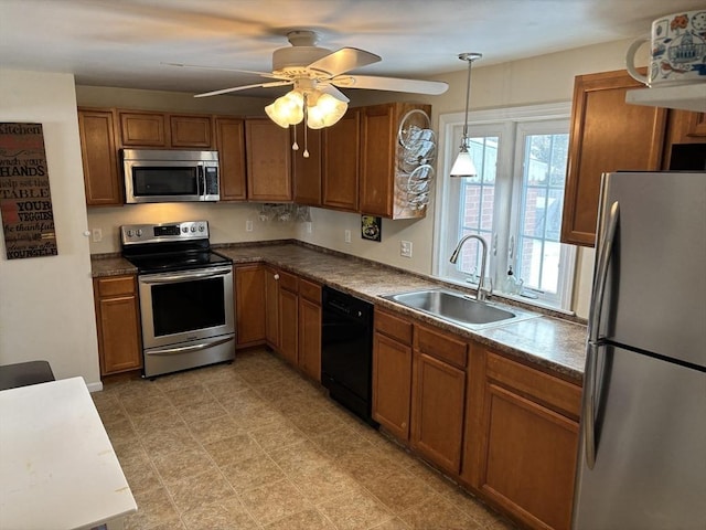 kitchen featuring a sink, hanging light fixtures, appliances with stainless steel finishes, brown cabinets, and dark countertops