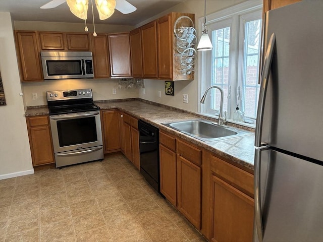 kitchen featuring stainless steel appliances, a sink, decorative light fixtures, and brown cabinets