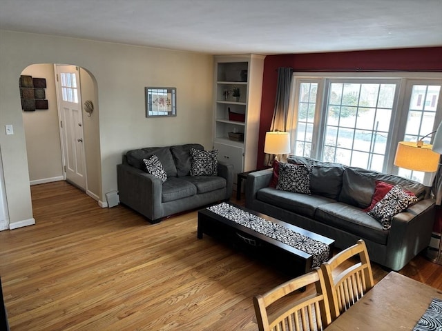 living area featuring baseboards, arched walkways, and wood finished floors