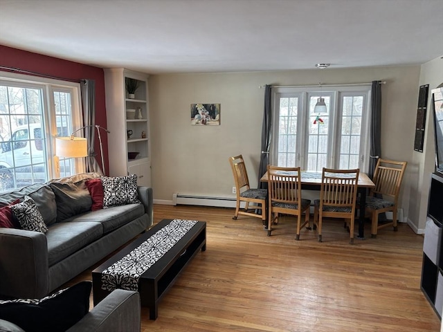 living room with baseboard heating, light wood-type flooring, and baseboards