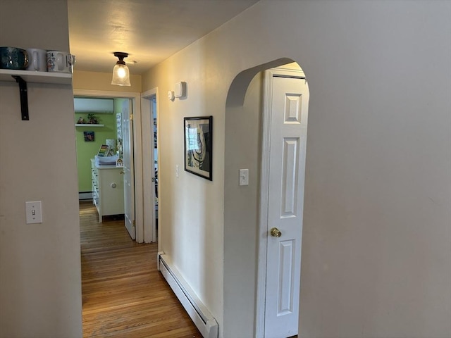 hallway featuring a baseboard radiator, a baseboard heating unit, arched walkways, and wood finished floors