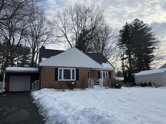 view of front of home featuring brick siding, a chimney, an attached garage, and aphalt driveway