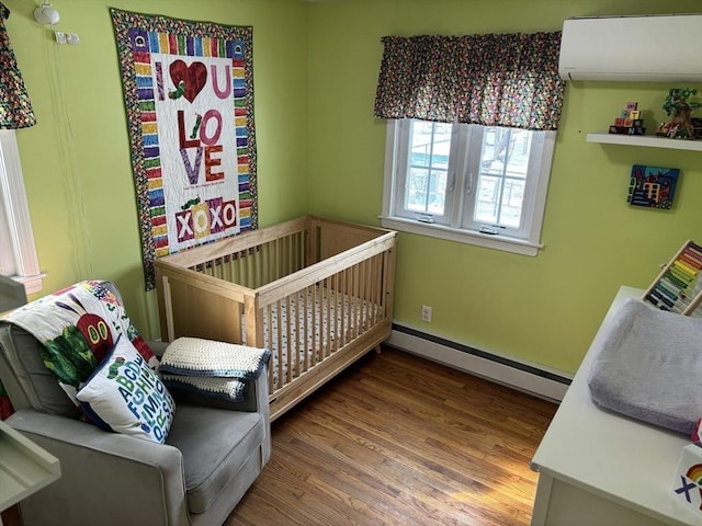 bedroom featuring an AC wall unit, baseboards, baseboard heating, and wood finished floors