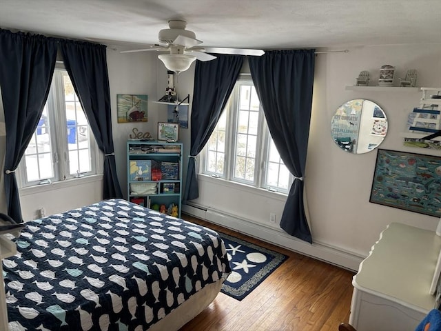 bedroom with ceiling fan, a baseboard radiator, wood finished floors, and baseboards