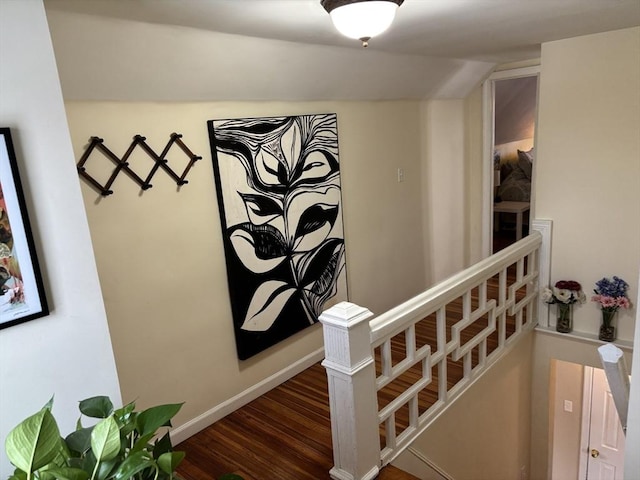 corridor with dark wood-type flooring, baseboards, vaulted ceiling, and an upstairs landing