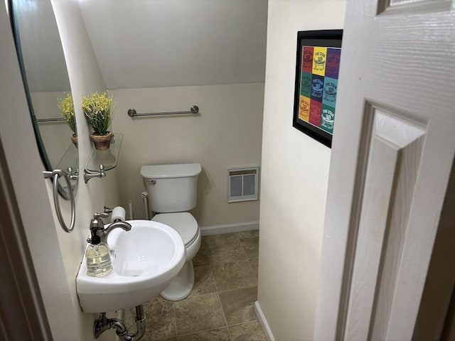 bathroom with lofted ceiling, a sink, toilet, and baseboards