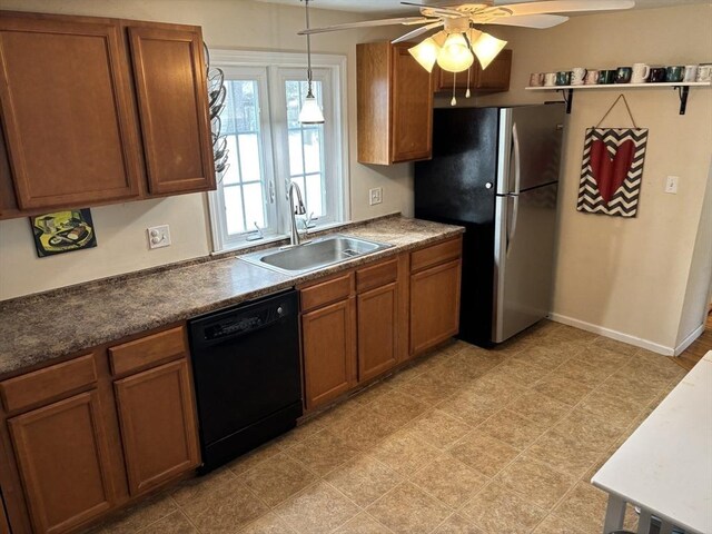 kitchen featuring black dishwasher, dark countertops, brown cabinets, freestanding refrigerator, and a sink