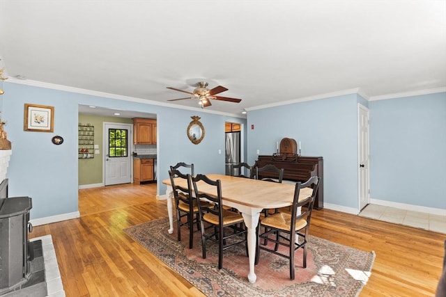 2025 S St, Bridgewater, MA 02324 - dining space featuring light wood-type flooring, ceiling fan, baseboards, crown molding, and a wood stove