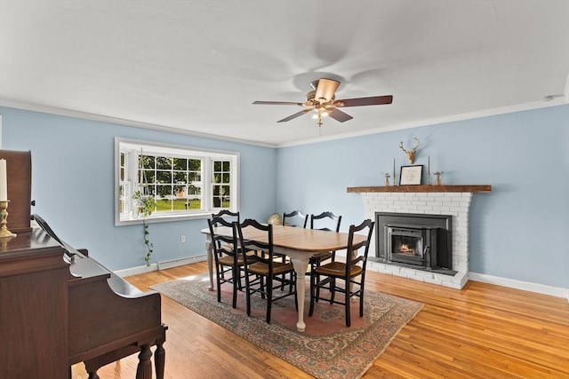 2025 S St, Bridgewater, MA 02324 - dining area with a ceiling fan, a brick fireplace, baseboards, crown molding, and light wood-type flooring