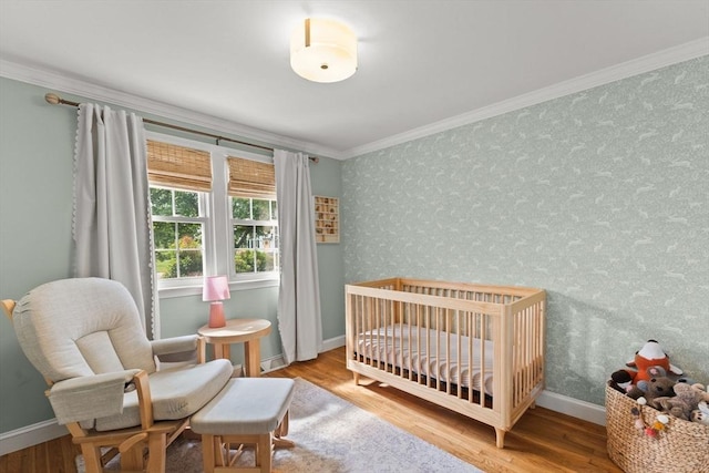 2025 S St, Bridgewater, MA 02324 - bedroom with ornamental molding, wood finished floors, a nursery area, baseboards, and wallpapered walls