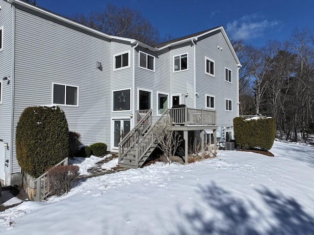 snow covered back of property featuring stairs, central AC unit, and a wooden deck