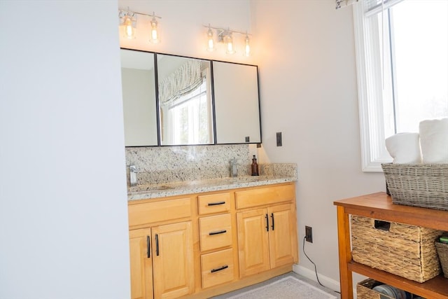 bathroom with tasteful backsplash, baseboards, and a sink