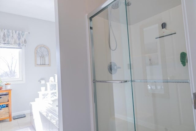 bathroom featuring a garden tub, a shower stall, baseboards, and tile patterned floors