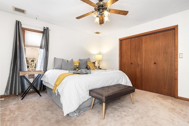 bedroom with a closet, light carpet, ceiling fan, and visible vents