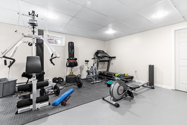 workout area with a paneled ceiling and baseboards