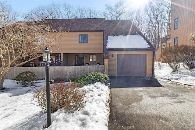 rustic home featuring a garage, driveway, and fence