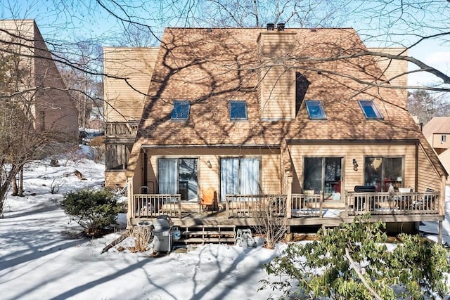 view of front facade featuring a deck, a shingled roof, and a chimney