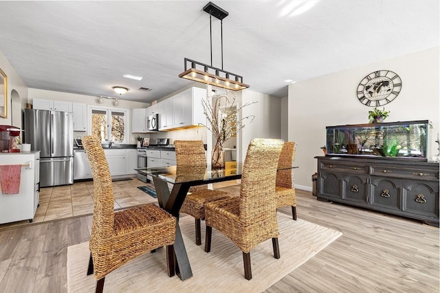 dining area with light wood-style floors and visible vents